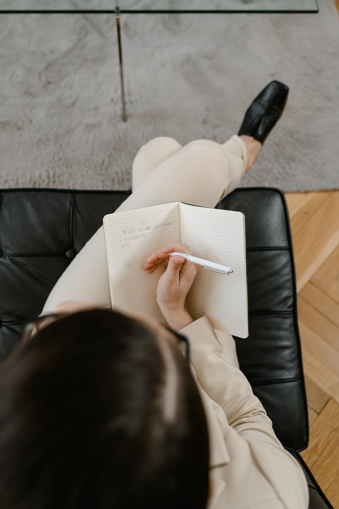 Pessoa sentada relaxada escrevendo em um caderno, representando reflexão pessoal.